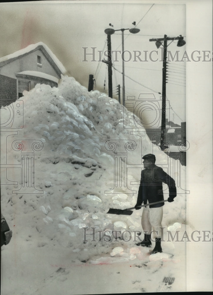 1962 Parking lot attendant shovels snow pile in South Bend, Indiana - Historic Images