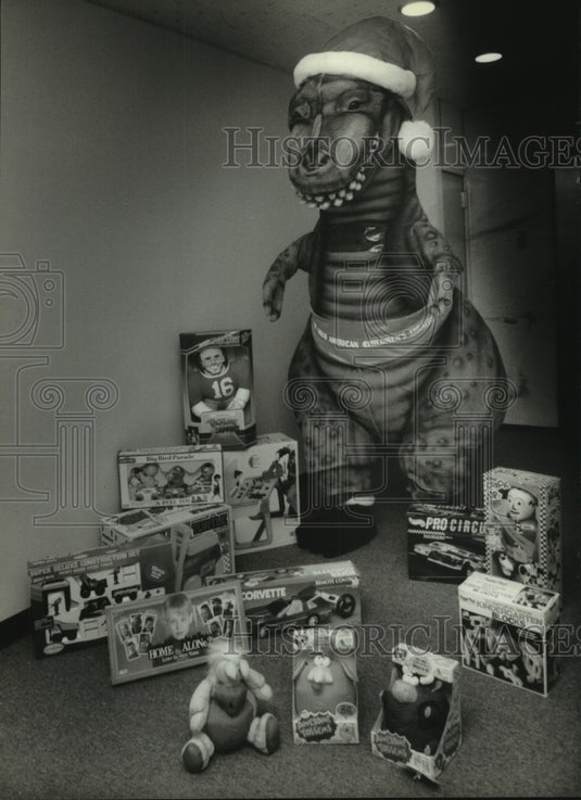 1993 Chad Bunker playing Santasaurus shows off some Christmas toys - Historic Images