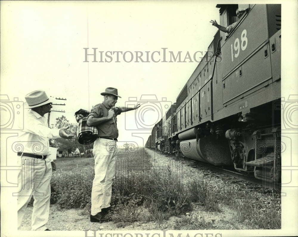 1970, John Dunlap and William Duncan wave at train, Fate, Texas - Historic Images