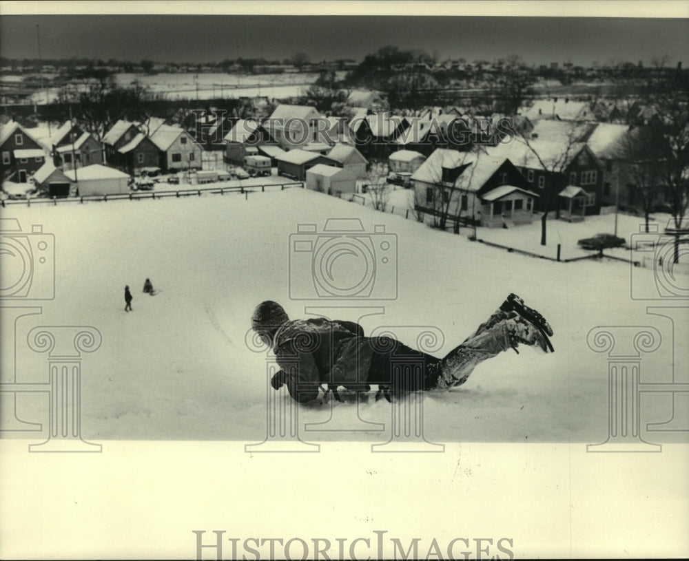 1983 Warren Burton sleds down hill near N. 38th St and Park Hill Ave - Historic Images