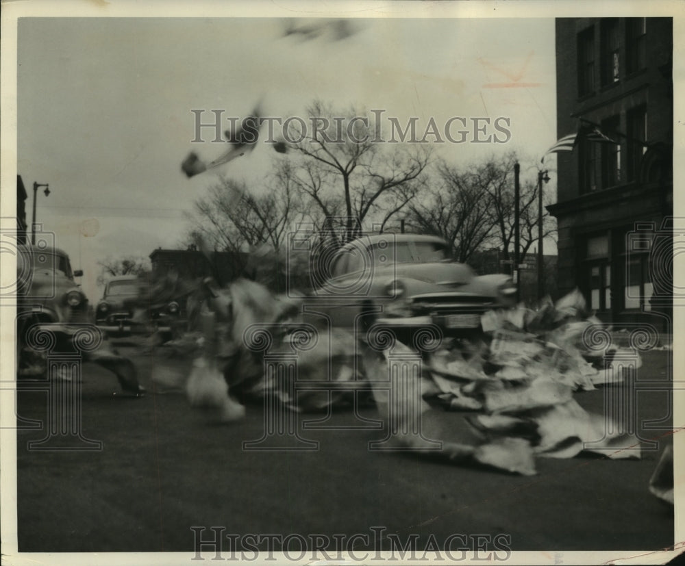 1954 Press Photo Car drives through wind blown papers, N. Milwaukee St Milwaukee - Historic Images