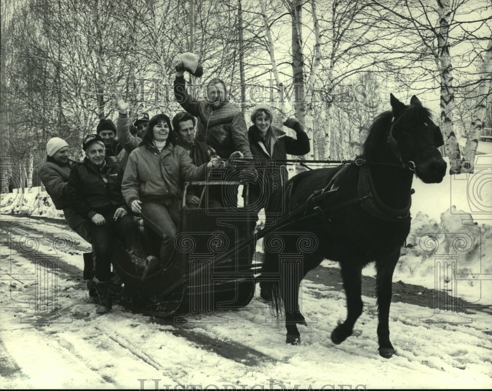 1984 Group of people on sled pulled by horse on snowy road - Historic Images