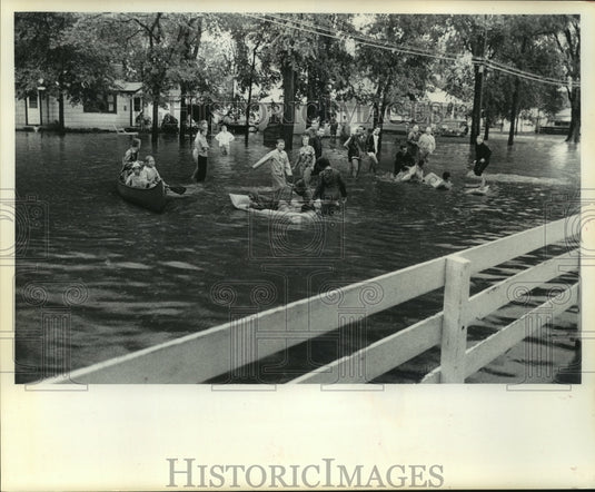 1984, Children canoe down flooded street, Milwaukee county - Historic Images