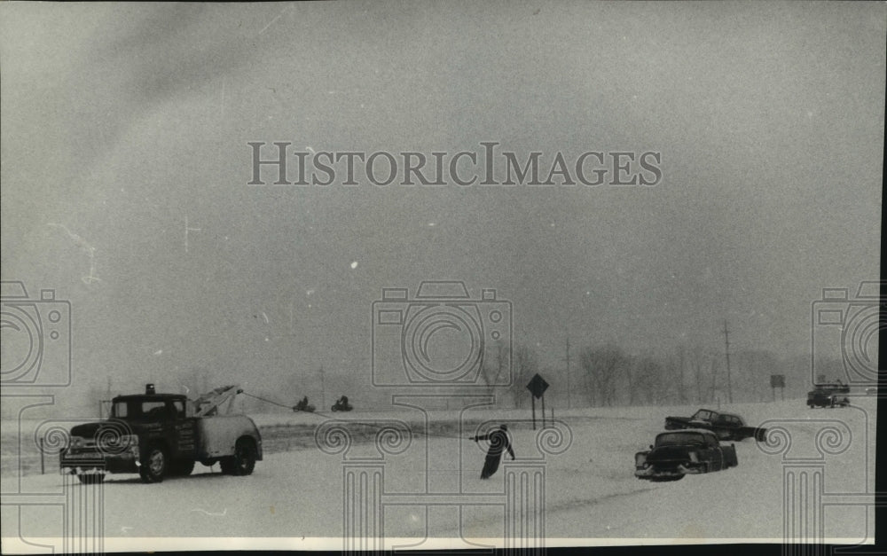 1965 Press Photo Tow truck operator stretches across Interstate 94 in Milwaukee- Historic Images