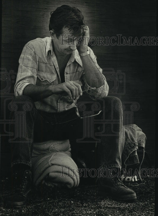 1988 Press Photo Gene Quimby sits on bedroll waiting to catch a boxcar - Historic Images