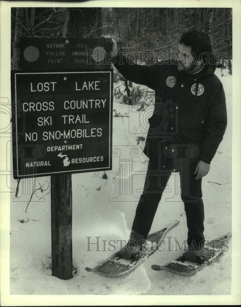 1986 Press Photo Don Ingle, inspecting a trail sign with snowshoes on, Michigan. - Historic Images