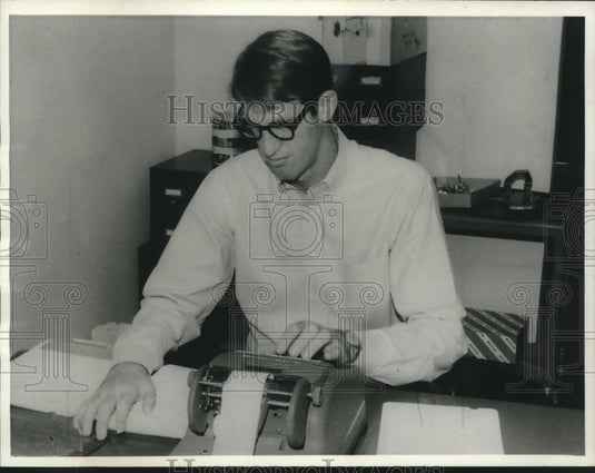 1965, Bob Swaffar at desk with partial use of arm replacement. - Historic Images