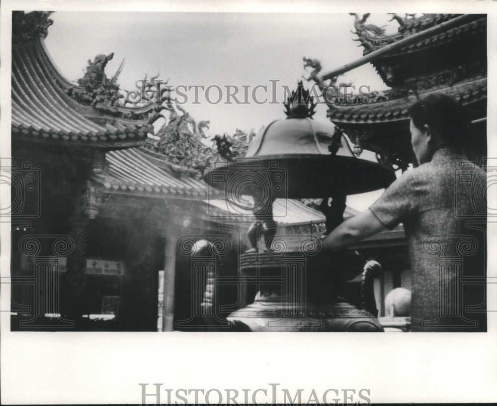 1970, Chinese woman places joss stick at Lungshan Temple, Taipei - Historic Images
