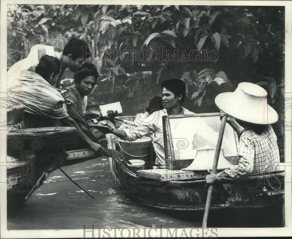 1972 Press Photo Waterborne peddlers trade with people on porches in Thailand - Historic Images
