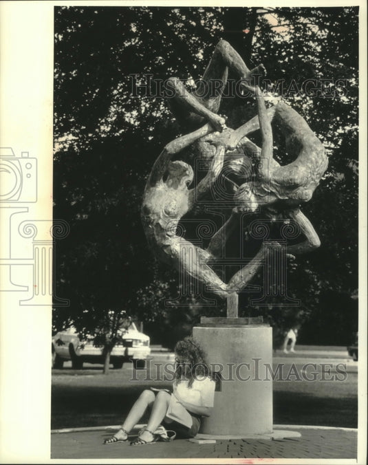 1991 Student sits by statue titled "Sprites" at UW Eau Claire - Historic Images