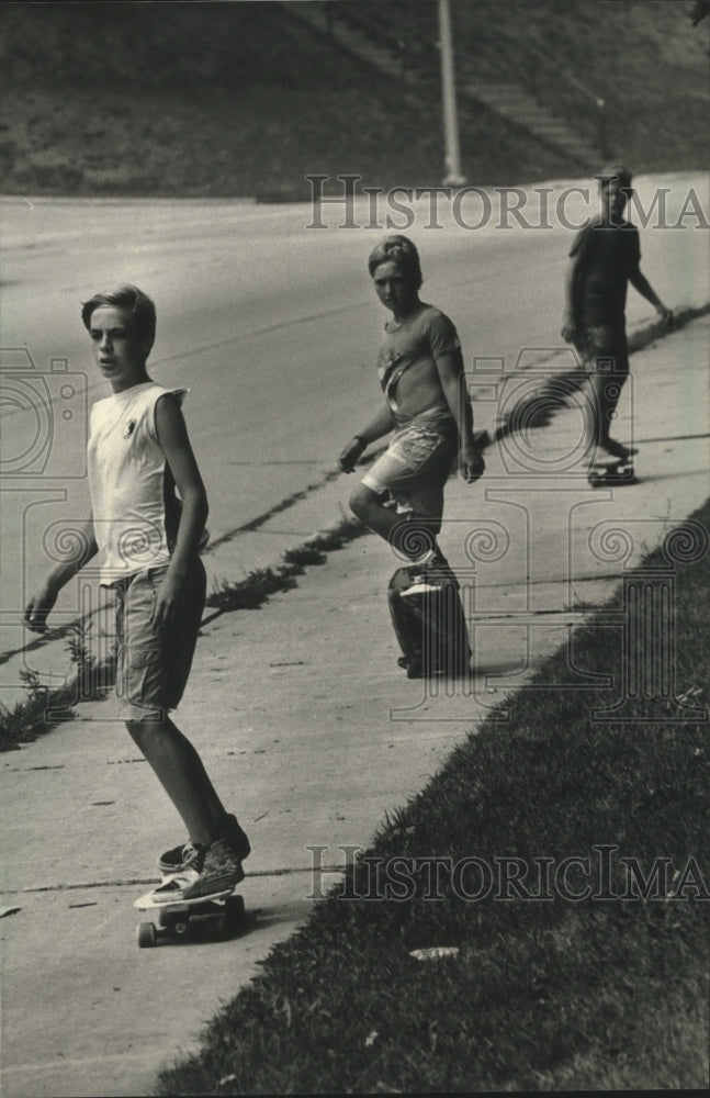 1988 Press Photo Three skateboarders rolling down main street Milwaukee - Historic Images