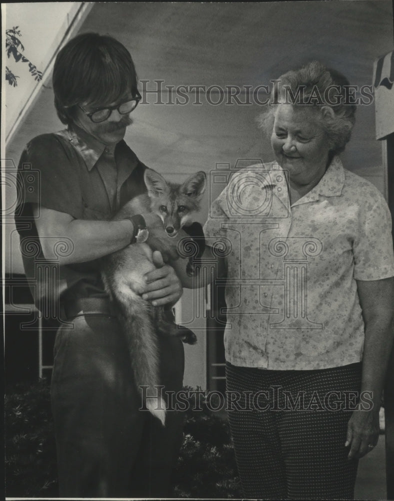 1976, Rodney Crousse and Mrs. George Speidel with baby red fox - Historic Images