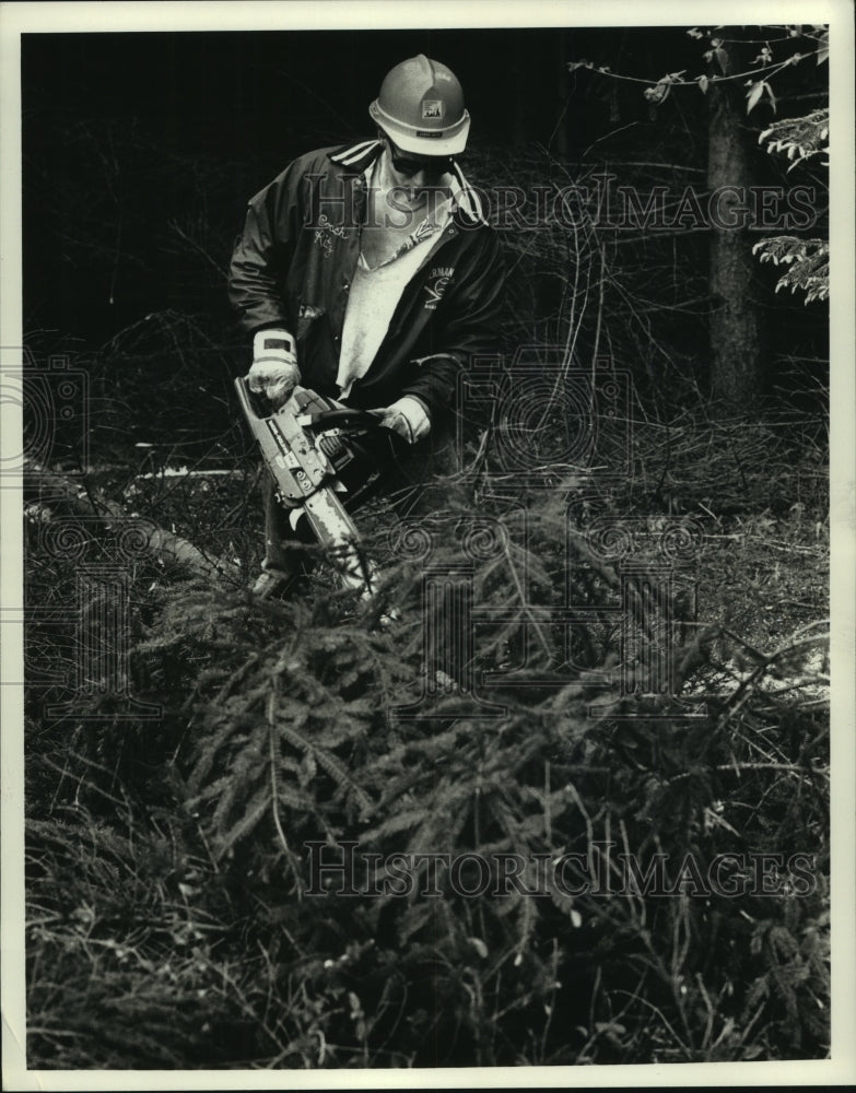 1990, Washington County Employee Jason Katz cuts trees with chain saw - Historic Images
