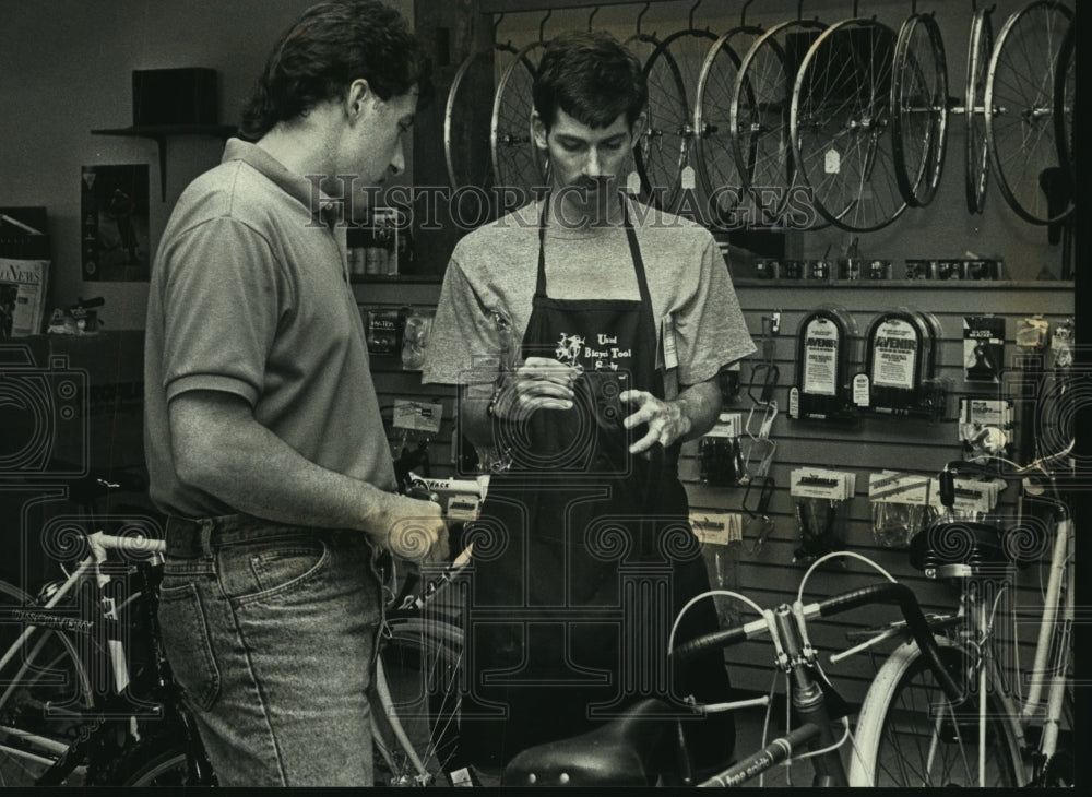 1992 Press Photo Brian Smith helps Mikw Walsh find bike accessories, Hartland - Historic Images