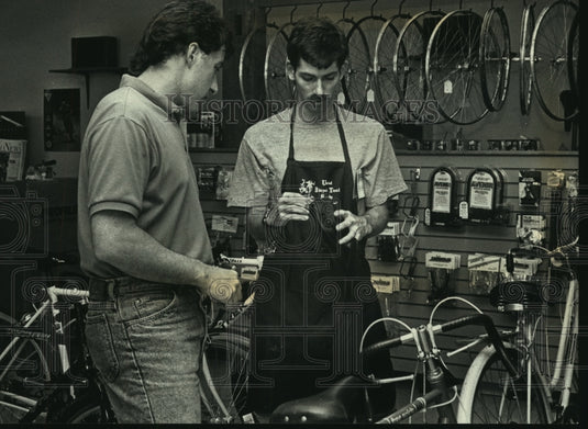 1992 Press Photo Brian Smith helps Mikw Walsh find bike accessories, Hartland - Historic Images