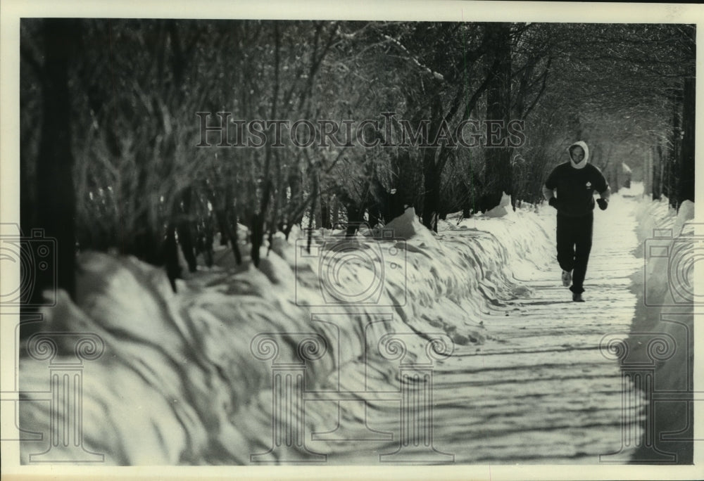 1979, David Brunner jogs on snow covered path Fox Point, Wisconsin - Historic Images