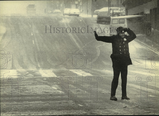 1982, Milwaukee policeman directs traffic in stormy, snowy weather - Historic Images