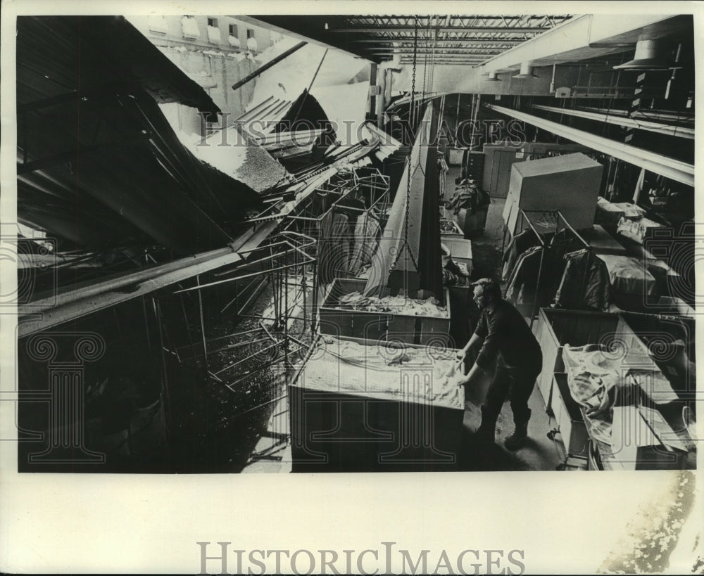 1965 Press Photo Goodwill Industries worker cleans where roof fell during storm - Historic Images