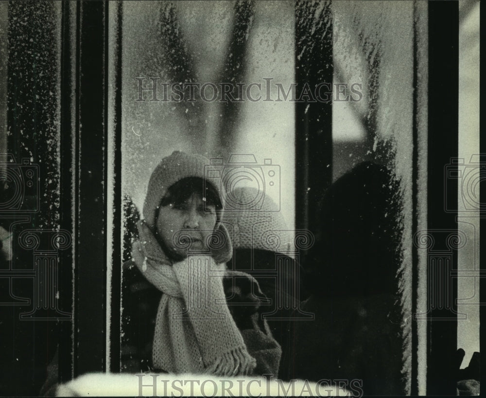 1983 A woman at a bus stop during a snowstorm in Milwaukee - Historic Images