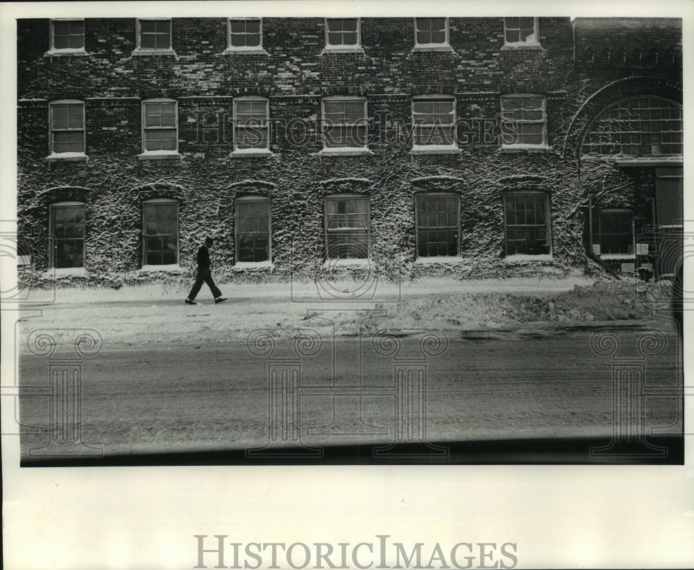 1964 Press Photo Man walks by snow covered Pfister &amp; Vogel Tanning Co. building - Historic Images