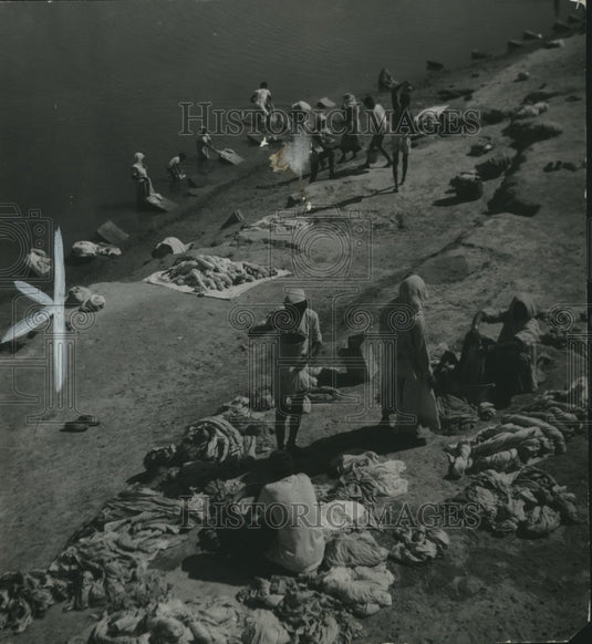 1939, Laundry workers wash clothes along Jamma river, India. - Historic Images