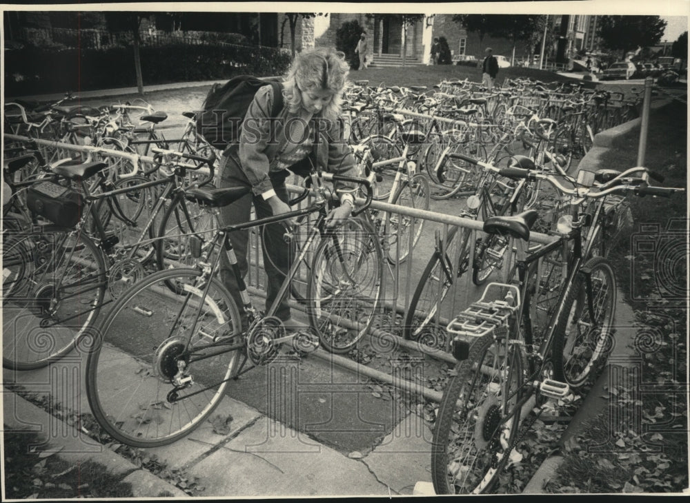 1985 UW-Madison student Dana Moore locks up bike on rack - Historic Images