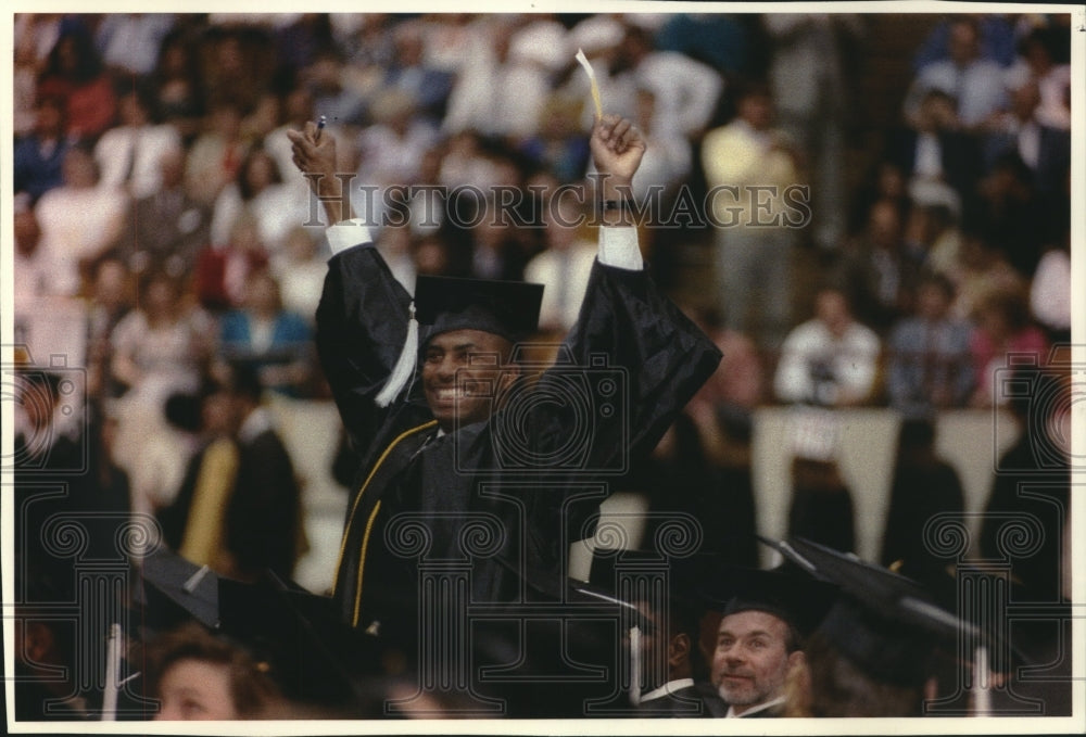 1993 Gary Hoover, standing  to cheer of students at graduation, UWM. - Historic Images