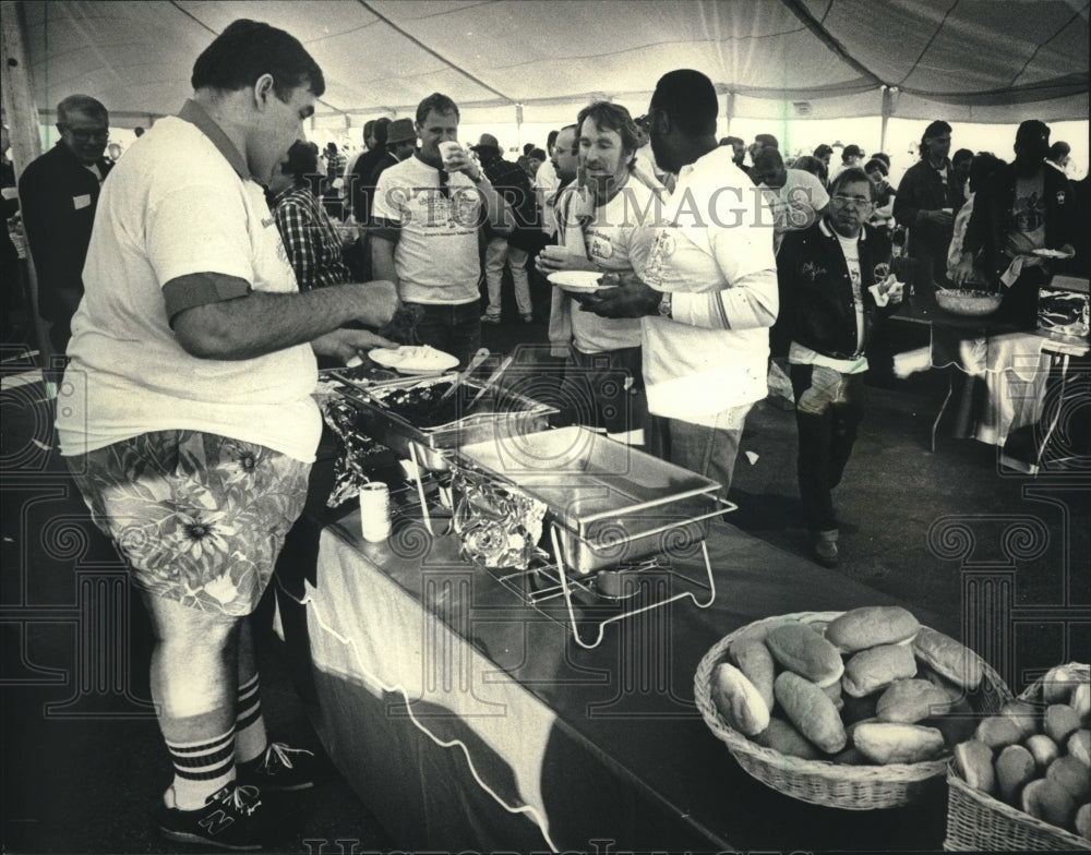 1988 David Schulz prepares hot dog at inauguration party with others - Historic Images