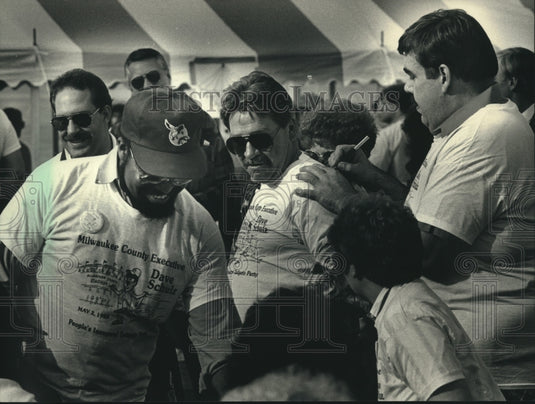 1988 Press Photo David Schulz autographing shirts of people in line, Milwaukee. - Historic Images