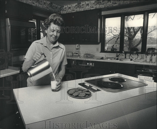 1976, Mrs. Senn pours glass of milk in her kitchen in Wisconsin - Historic Images