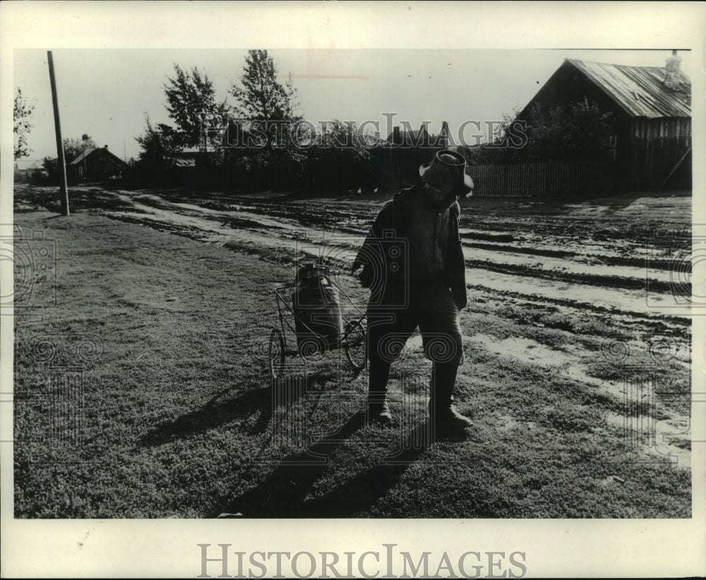 1969 Press Photo Elderly Russian Trudges Along Rural Dirt Road With Can Of Milk - Historic Images