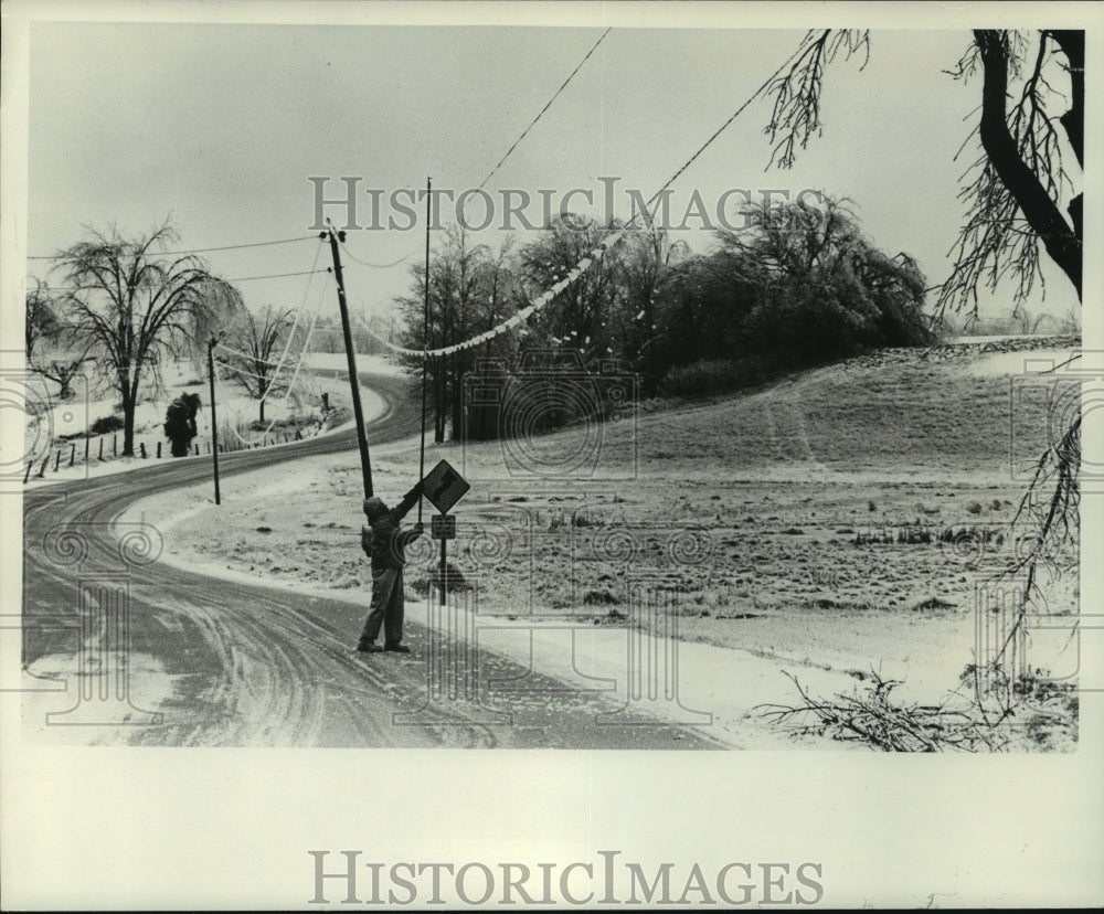 1976, worker knocks ice off lines on County Highway M, Wisconsin - Historic Images