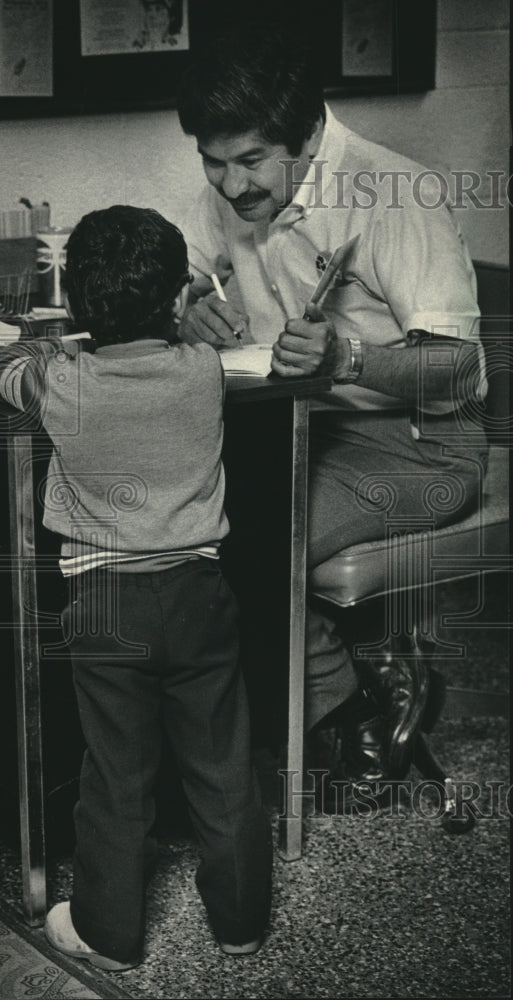 1985 Press Photo Manual Salas got a book for a child, United Community Center - Historic Images