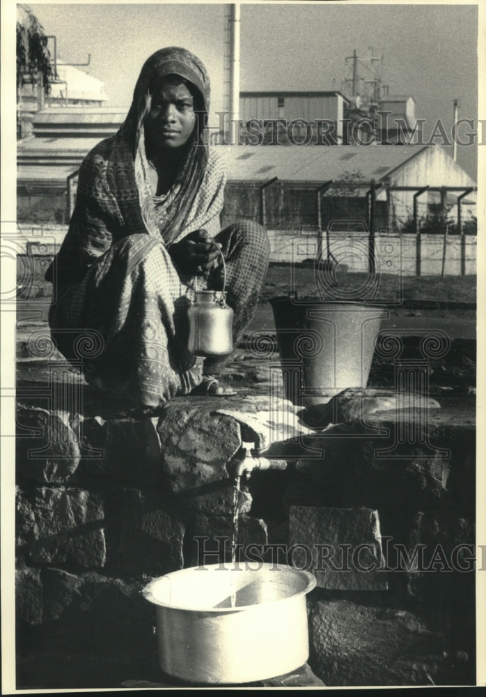 1987 Press Photo Slum dweller fills water consenters in Bhopal, India - Historic Images