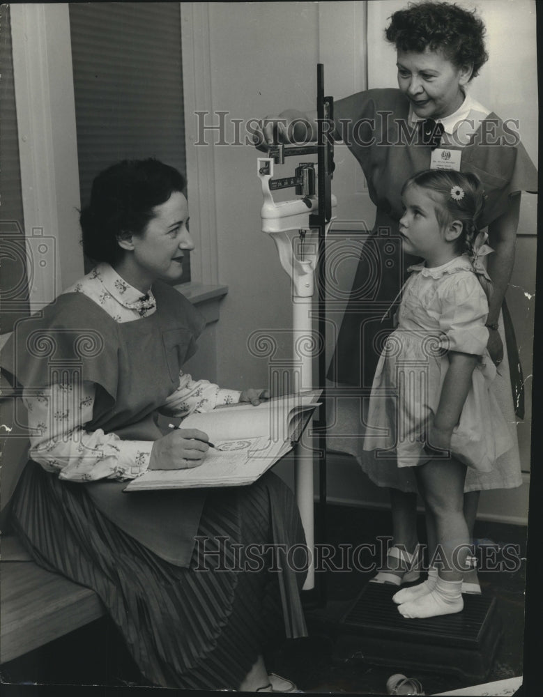 1955 School workers weighing girl in Shorewood, Wisconsin - Historic Images