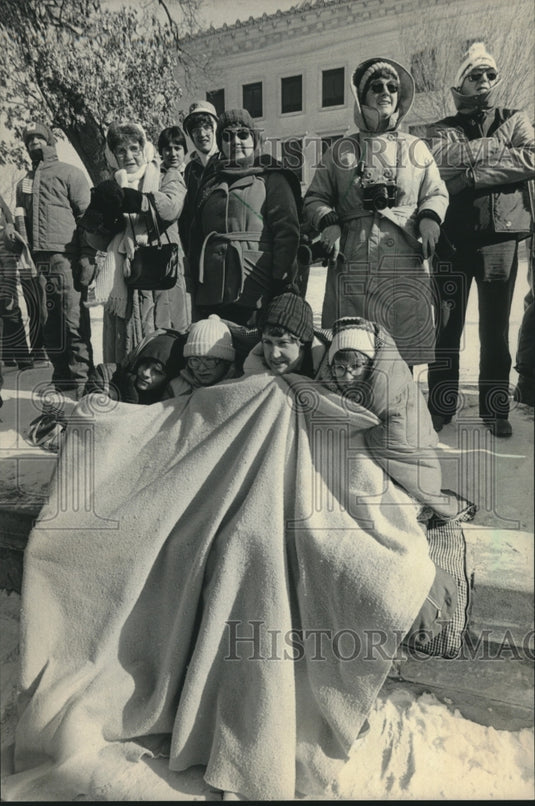 1984 Folks huddle to keep warm while waiting to see President Reagan - Historic Images