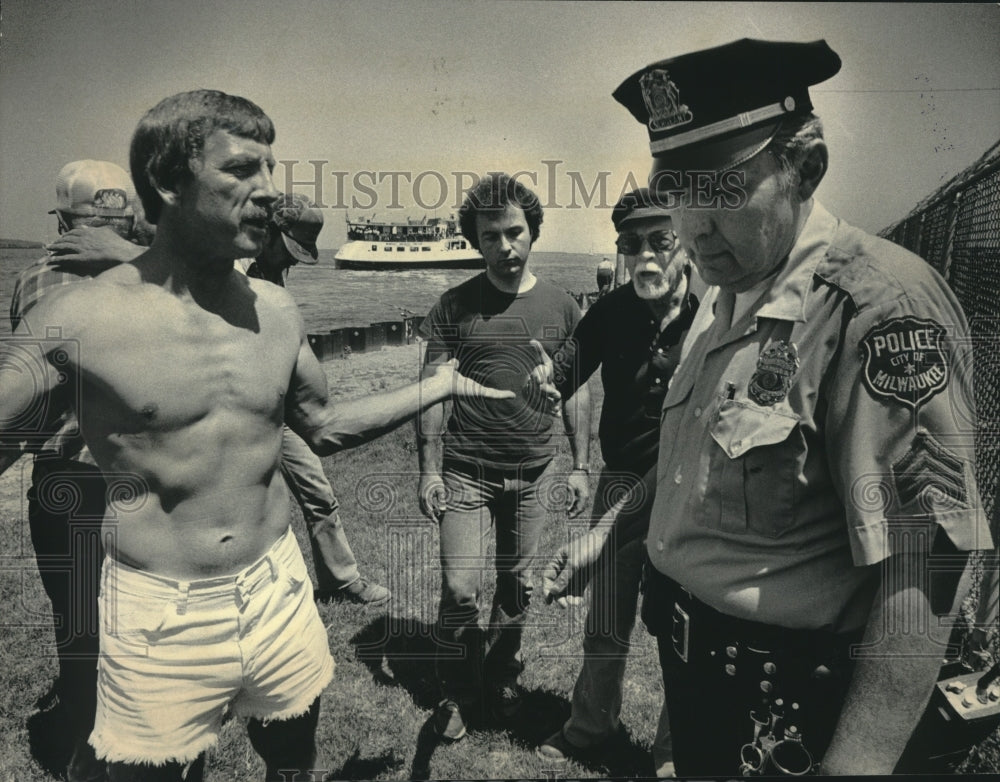 1984 Press Photo People watch fisherman Bruce Pulkkila argue with officer, WI - Historic Images