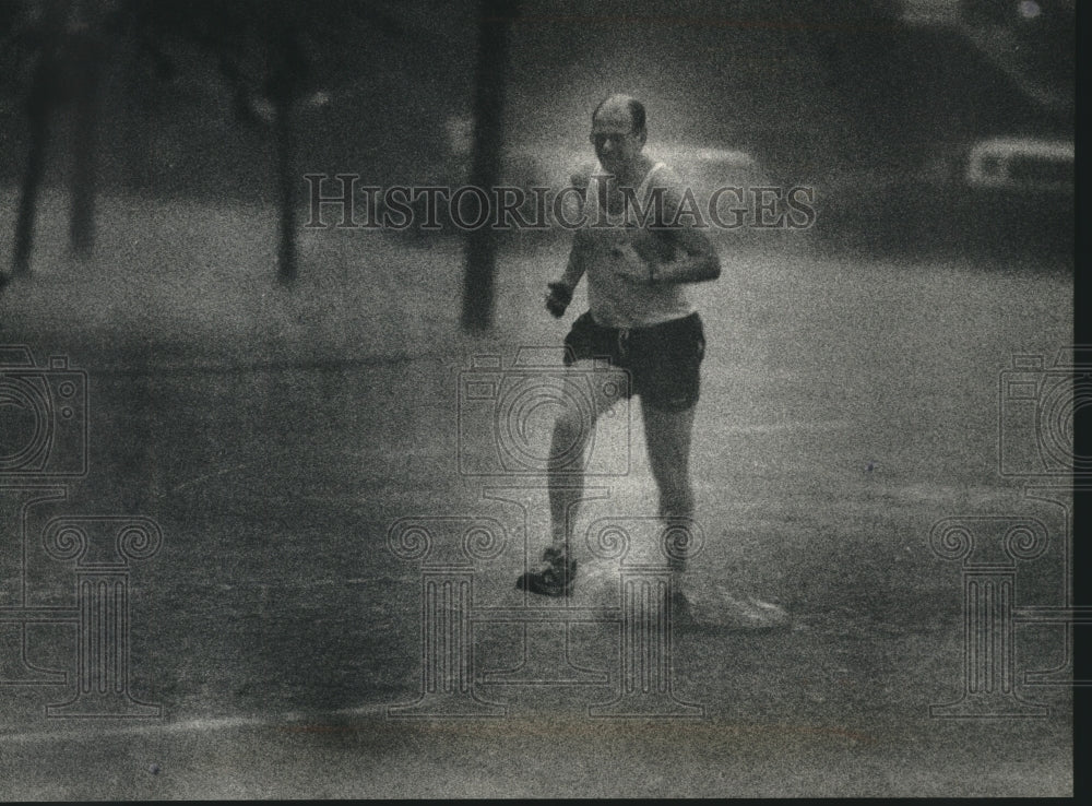 1992 Jogger running in the rain on East Wisconsin Ave in Milwaukee - Historic Images