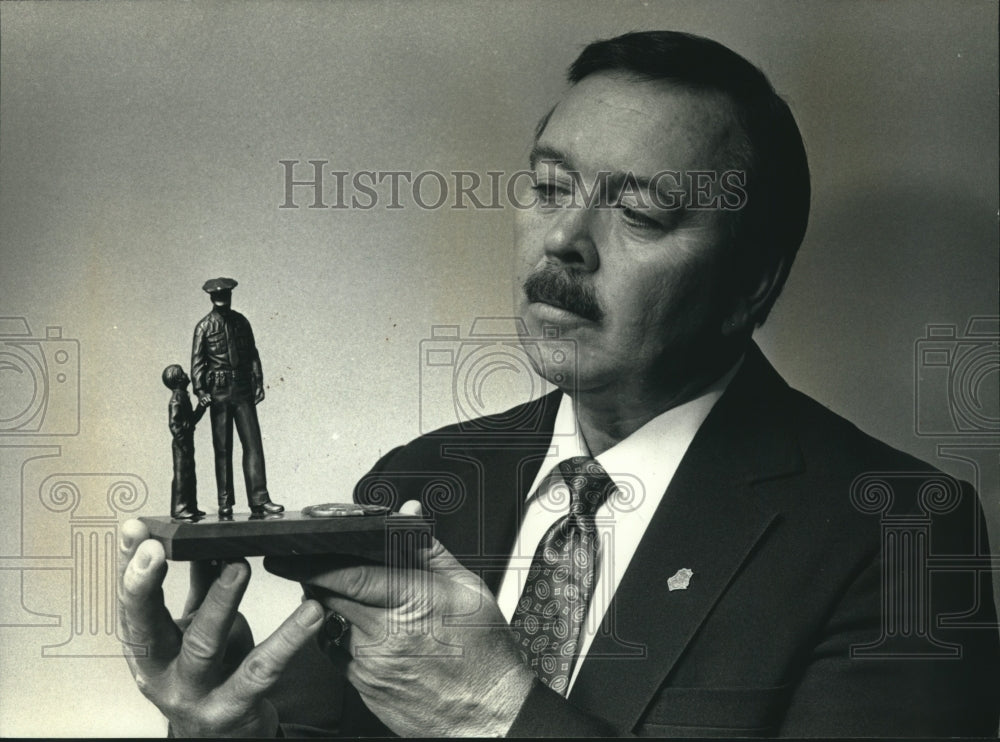 1991 Thomas H. Stigler Waukesha police chief, holds bronze statue - Historic Images