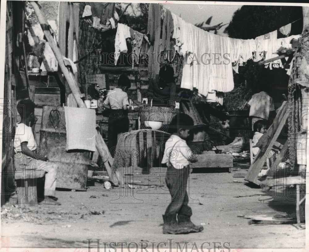 1961, Peruvian mother washes clothes while children play in Callao - Historic Images