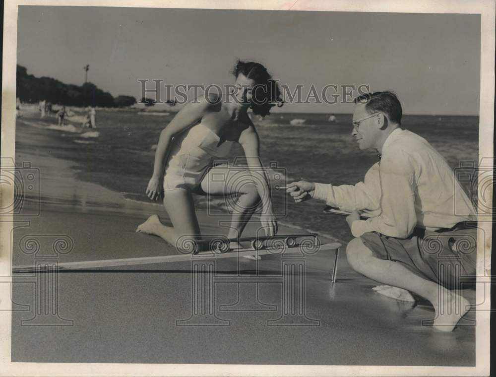 1953, Bob Riordan and Sue Trebbe measure beach at Lake Michigan. - Historic Images