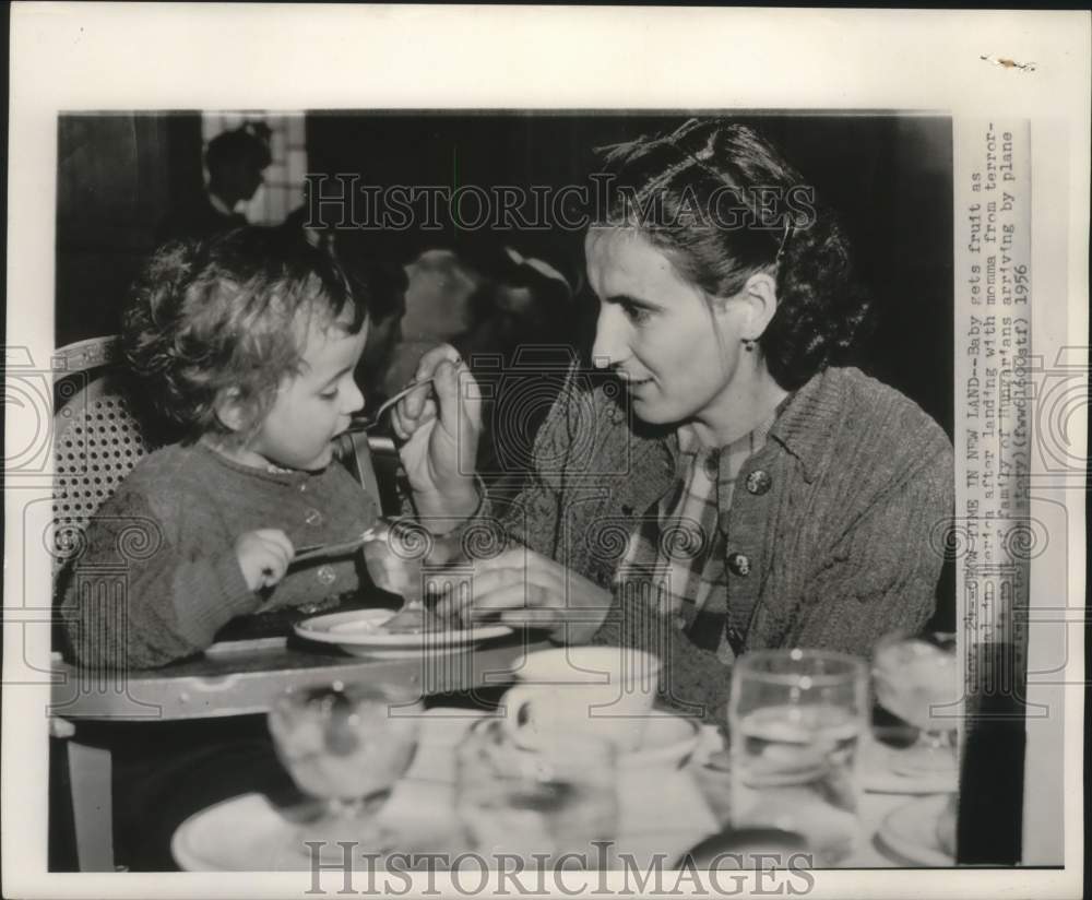 1956, Hungarian refugee mom feeds child fruit for meal, Milwaukee. - Historic Images