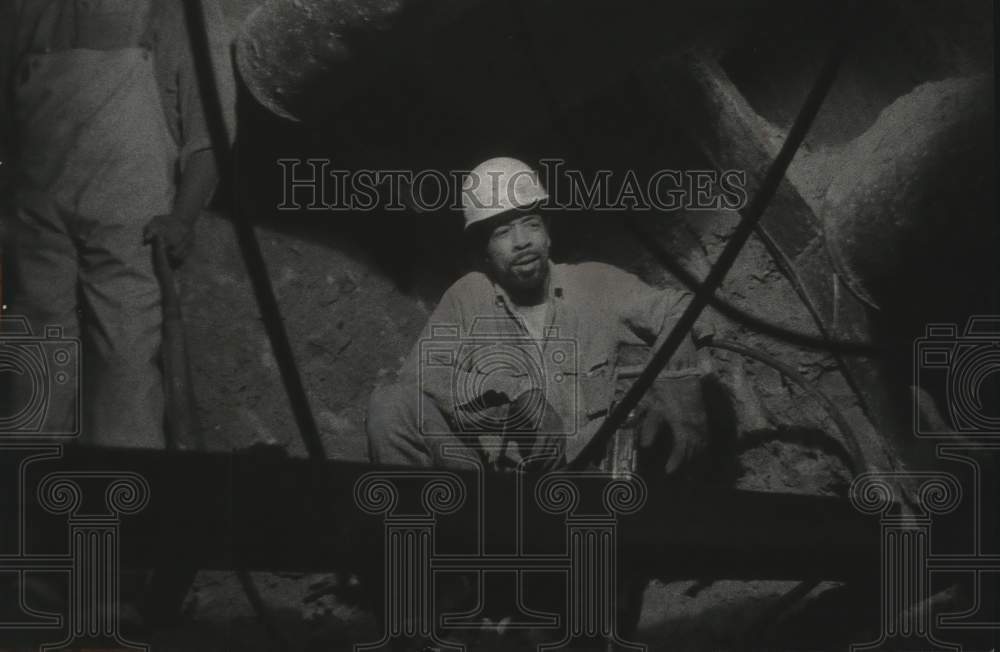 1975 Press Photo Miner waits for mucking machine to pickup loose dirt in tunnel - Historic Images