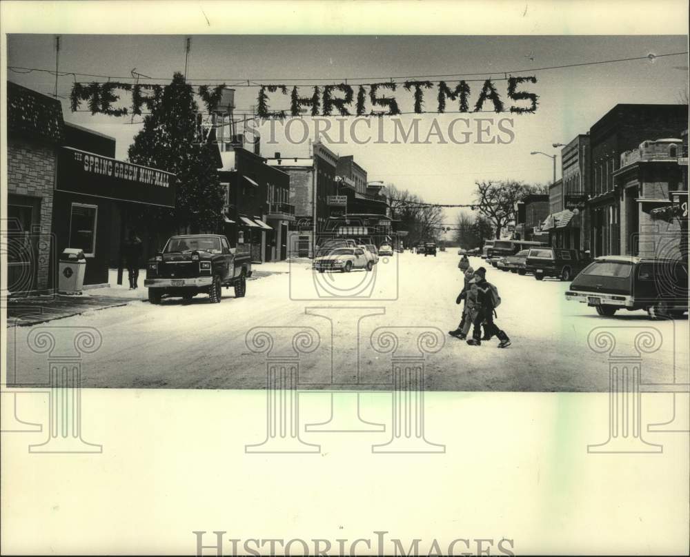 1983 Press Photo Under a Christmas banner, children cross street in Spring Green - Historic Images