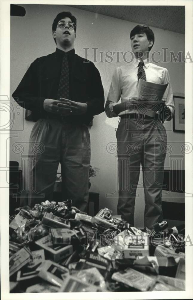 1992 Press Photo Victor Dejesus & Jamie Wall in front of pile of cigarette packs - Historic Images