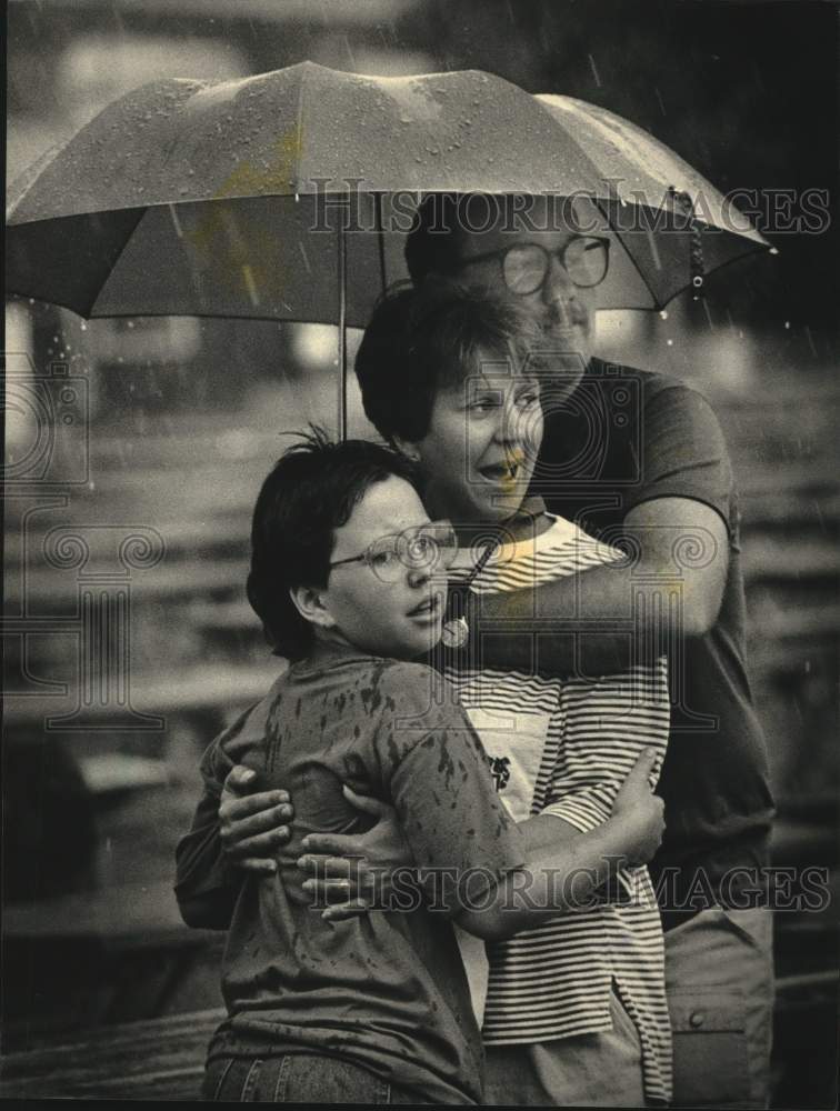 1987 Press Photo Gary Goetsch &amp; family huddle under umbrella at Summerfest. - Historic Images