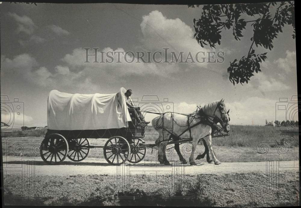 1968, Man rides in covered wagon pulled by two horses - mjc30106 - Historic Images