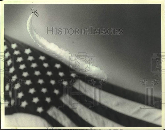 1983 Press Photo Biplane leaves smoke trail over United States Flag, Wisconsin - Historic Images