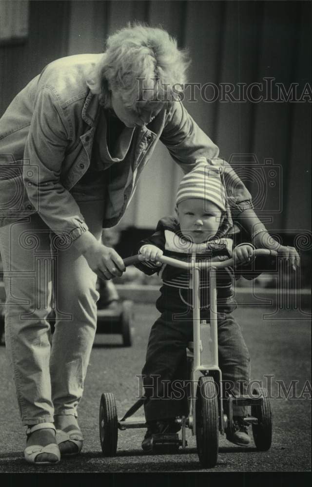 1985 Press Photo Toddler on tricycle &amp; day-care center worker, Rinkeby, Sweden - Historic Images