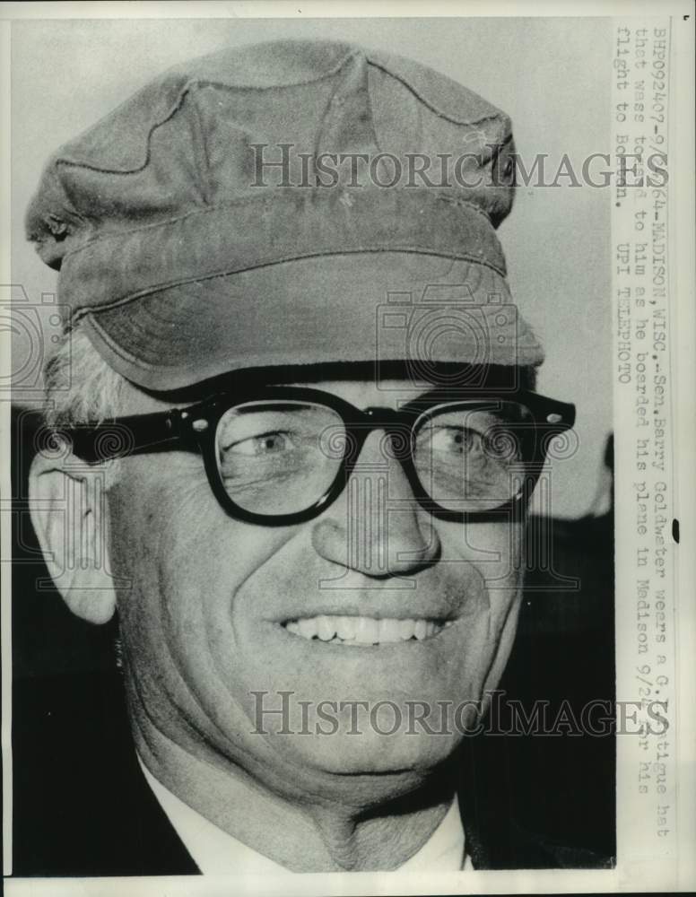 1964, Sen. Barry Goldwater wears a GI hat as he boards plane to rally - Historic Images